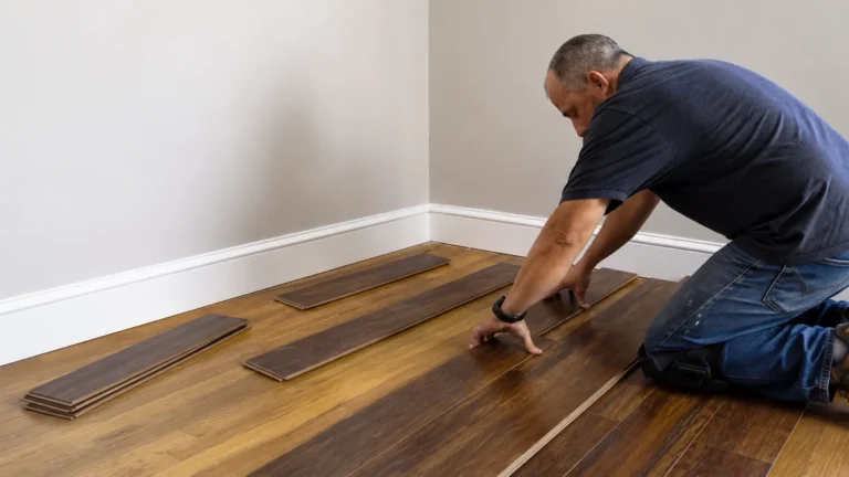 Installer laying dark stained planks across a room, with spare boards staged along the wall